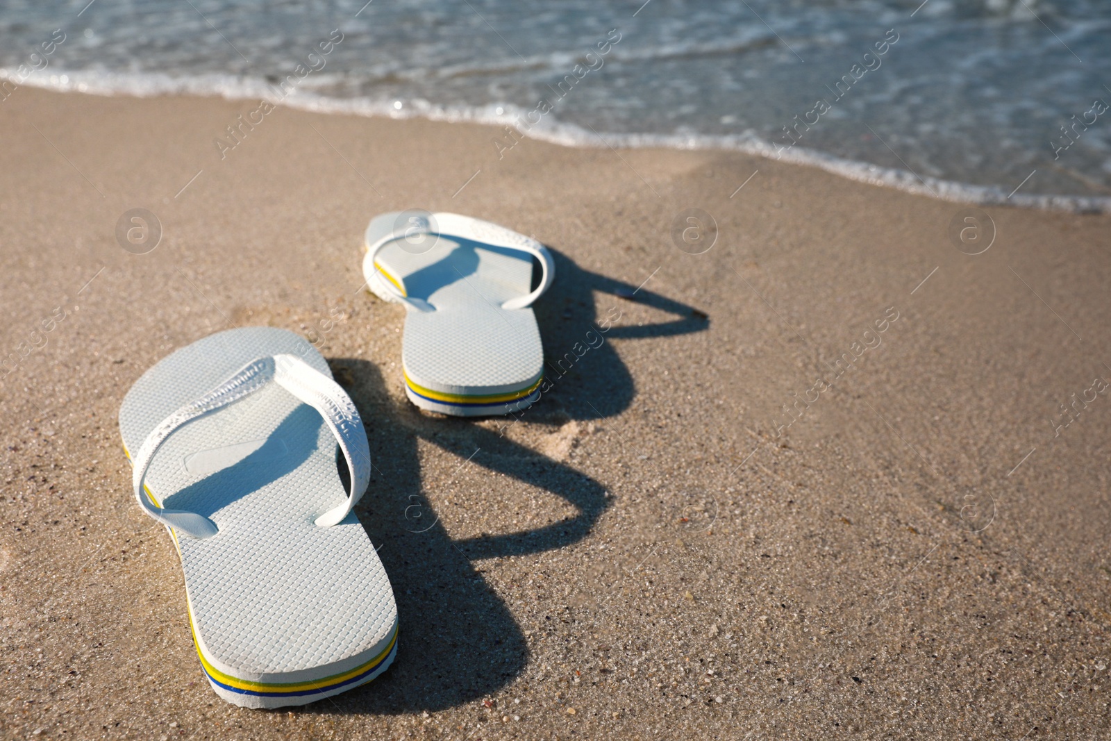 Photo of Pair of stylish flip flops on beach