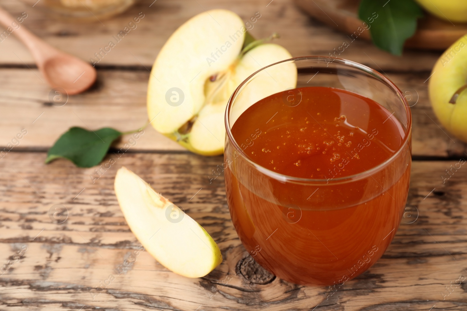 Photo of Glass of honey and apples on wooden table