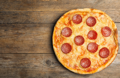 Photo of Tasty pepperoni pizza on wooden table, top view. Space for text