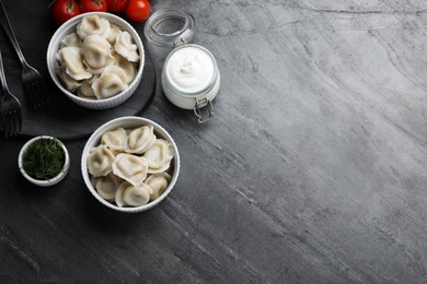 Photo of Tasty dumplings in bowls served on grey table, flat lay. Space for text