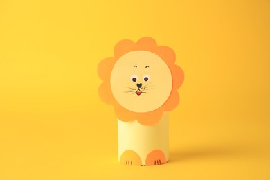 Toy lion made from toilet paper hub on yellow background. Children's handmade ideas