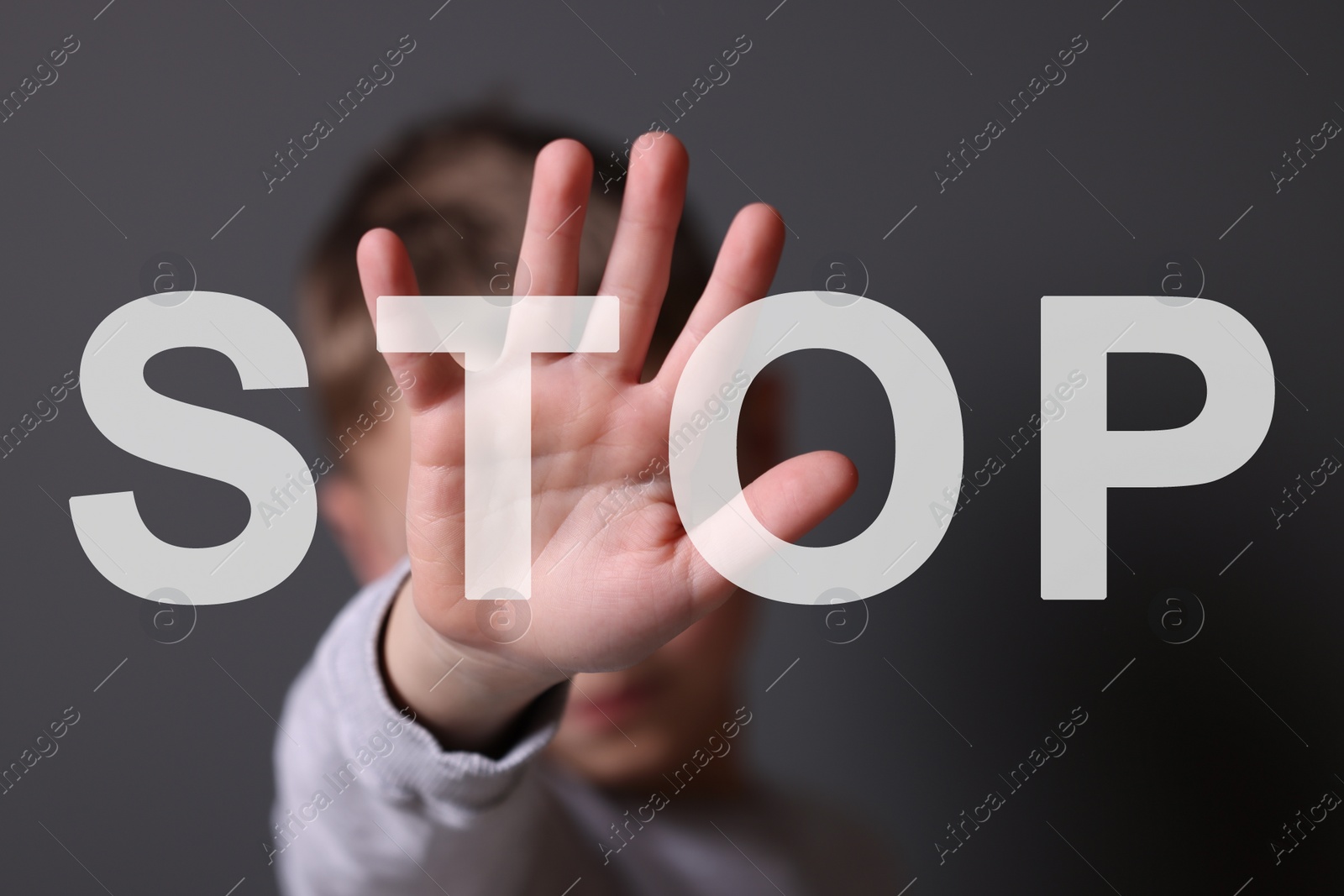 Image of No child abuse. Boy making stop gesture on grey background, selective focus