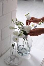 Photo of Woman taking beautiful flowers from vase indoors, closeup