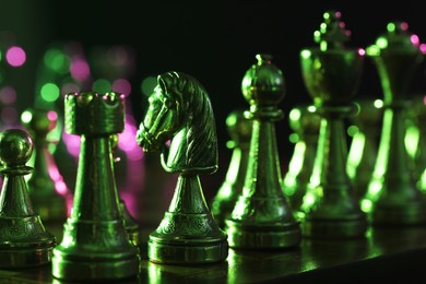 Photo of Chess pieces on checkerboard in color light, closeup