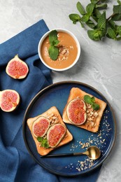 Photo of Tasty toasts served with fig, peanut butter and walnuts on light grey marble table, flat lay