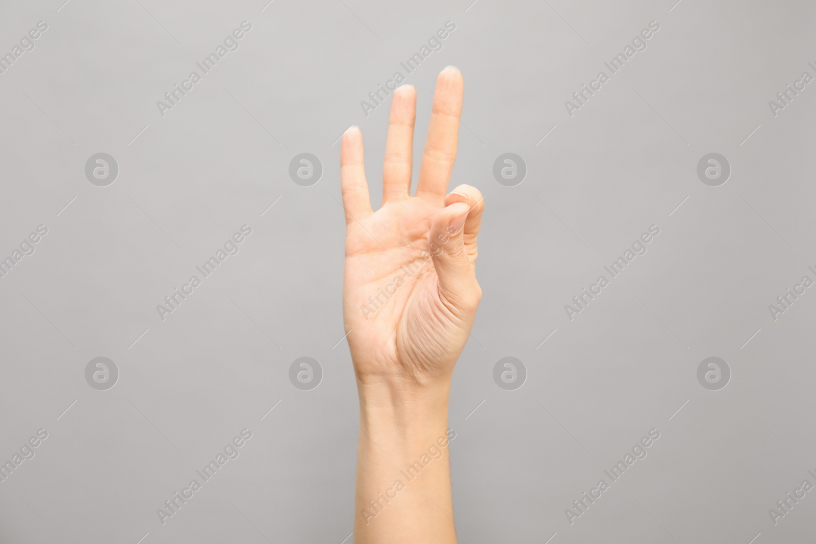 Photo of Woman showing number nine on grey background, closeup. Sign language