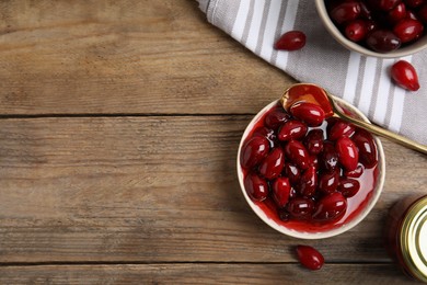 Delicious dogwood jam with berries on wooden table, flat lay. Space for text