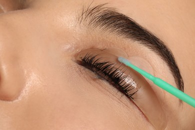 Photo of Young woman undergoing eyelash lamination, closeup. Professional service