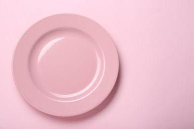 Photo of Empty ceramic plate on pink background, top view. Space for text
