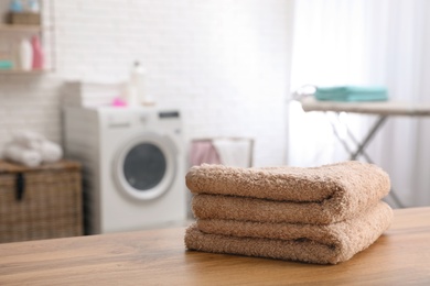 Stack of towels on table against blurred background, space for text