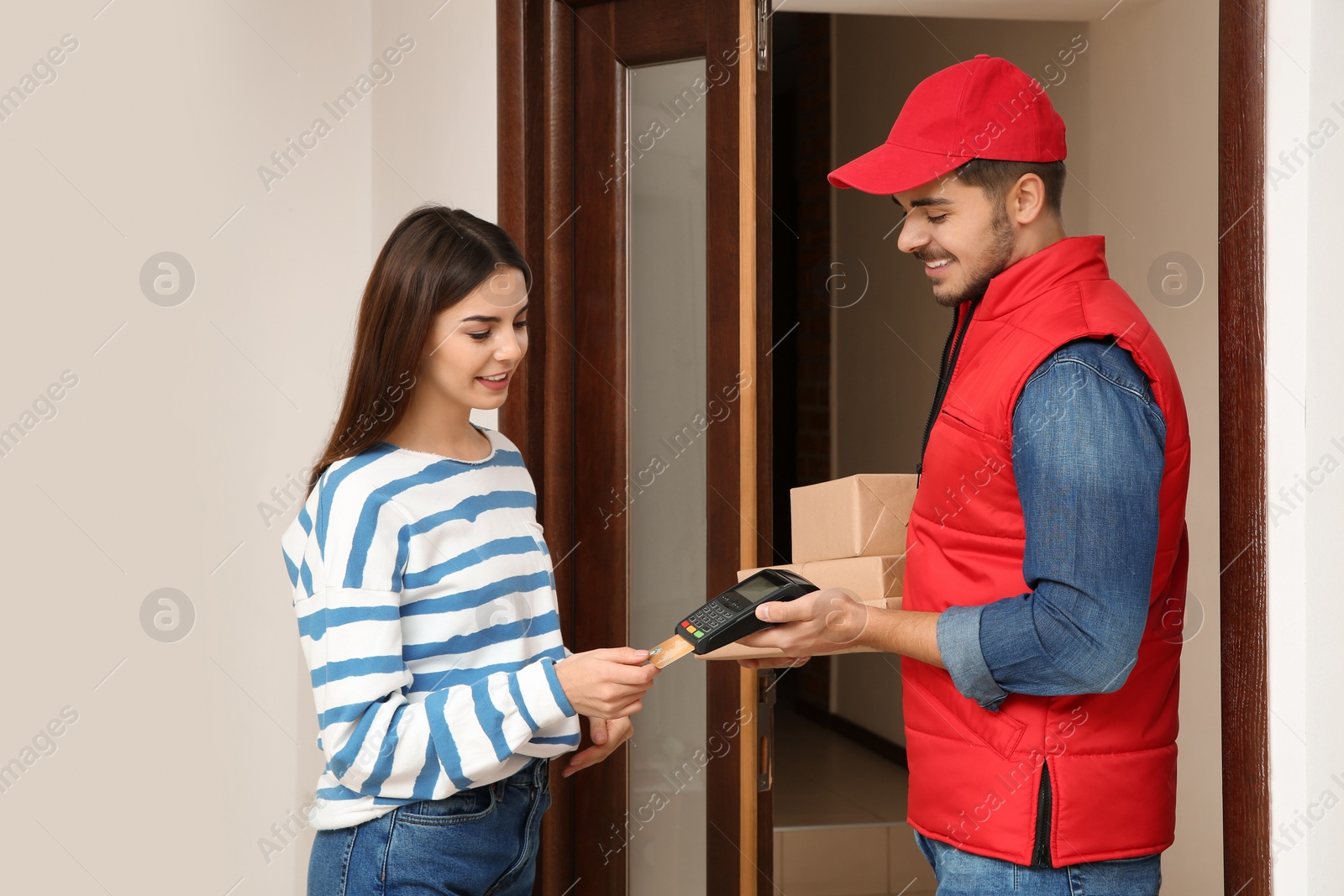 Photo of Young woman with credit card using bank terminal for delivery payment at doorway