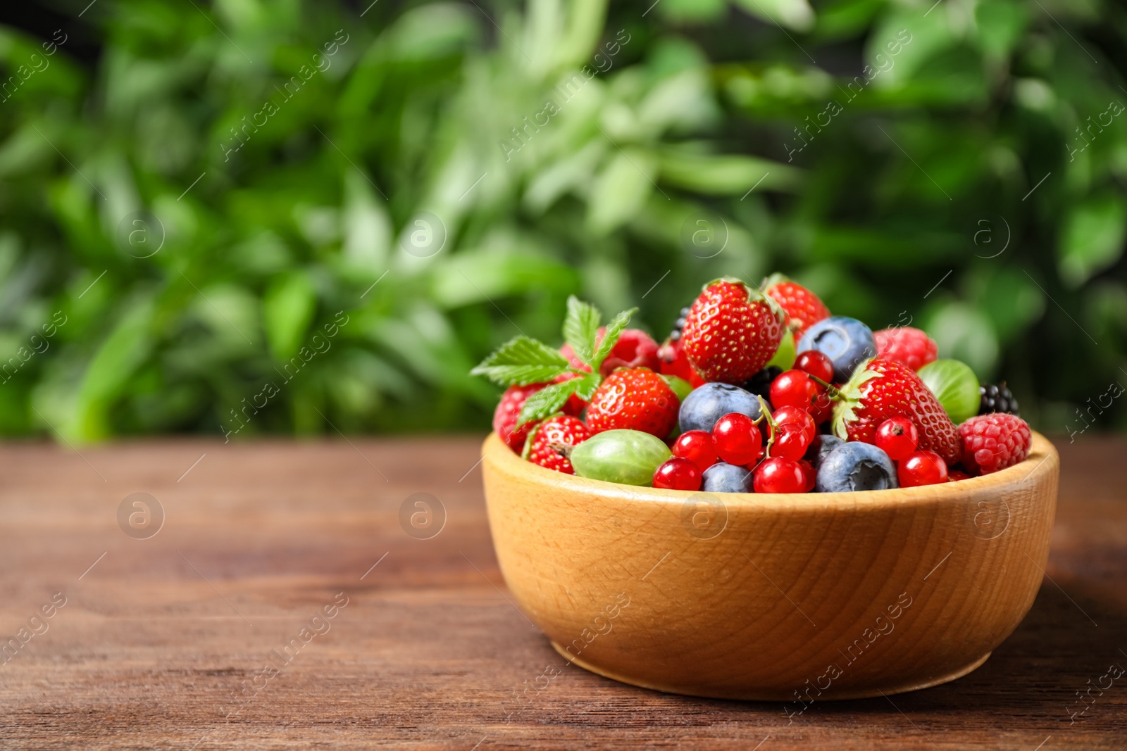 Photo of Mix of ripe berries on wooden table. Space for text