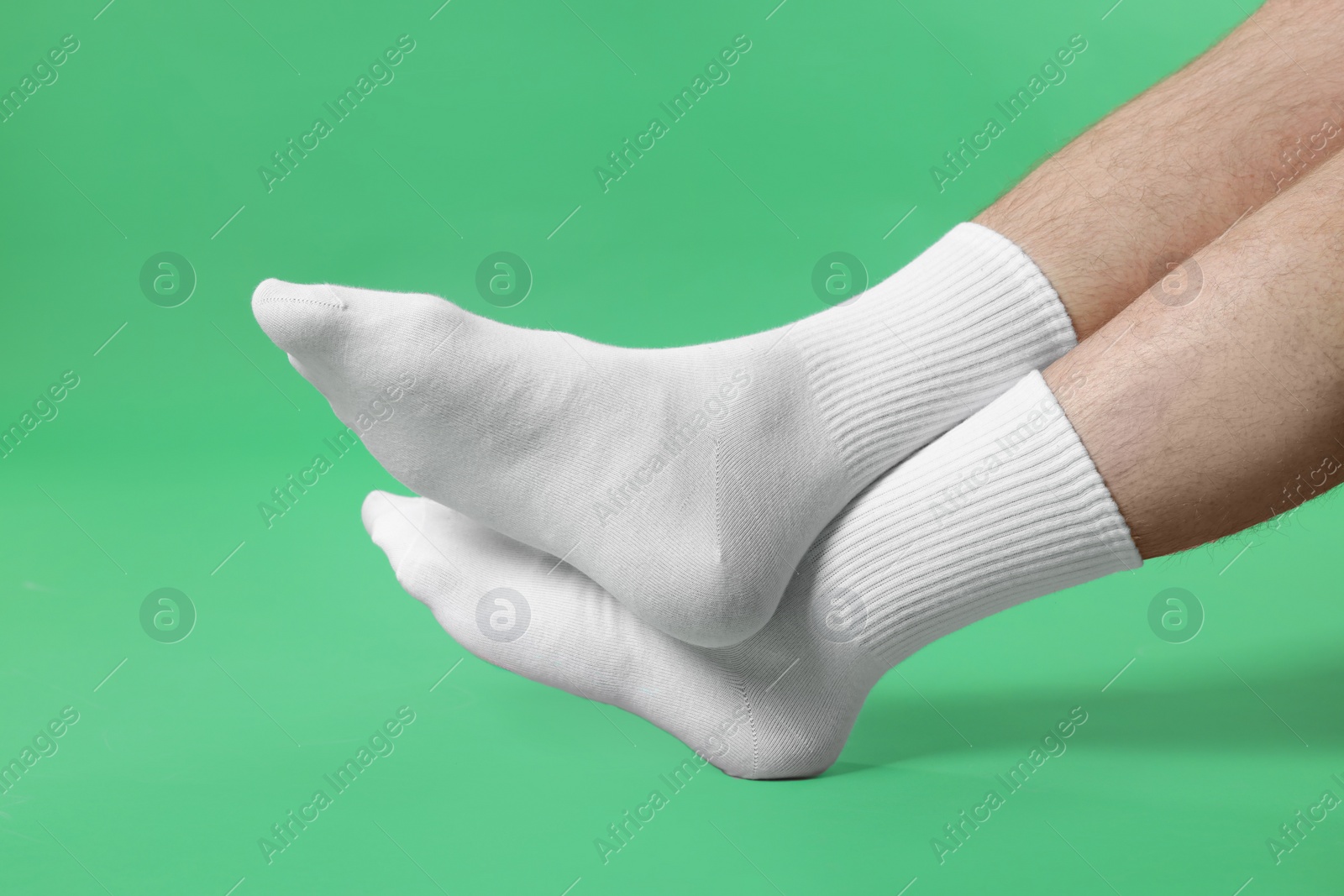 Photo of Man in stylish white socks on green background, closeup