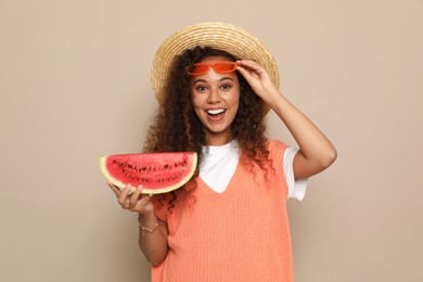 Photo of Beautiful young African American woman with slice of watermelon on beige background