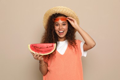 Beautiful young African American woman with slice of watermelon on beige background