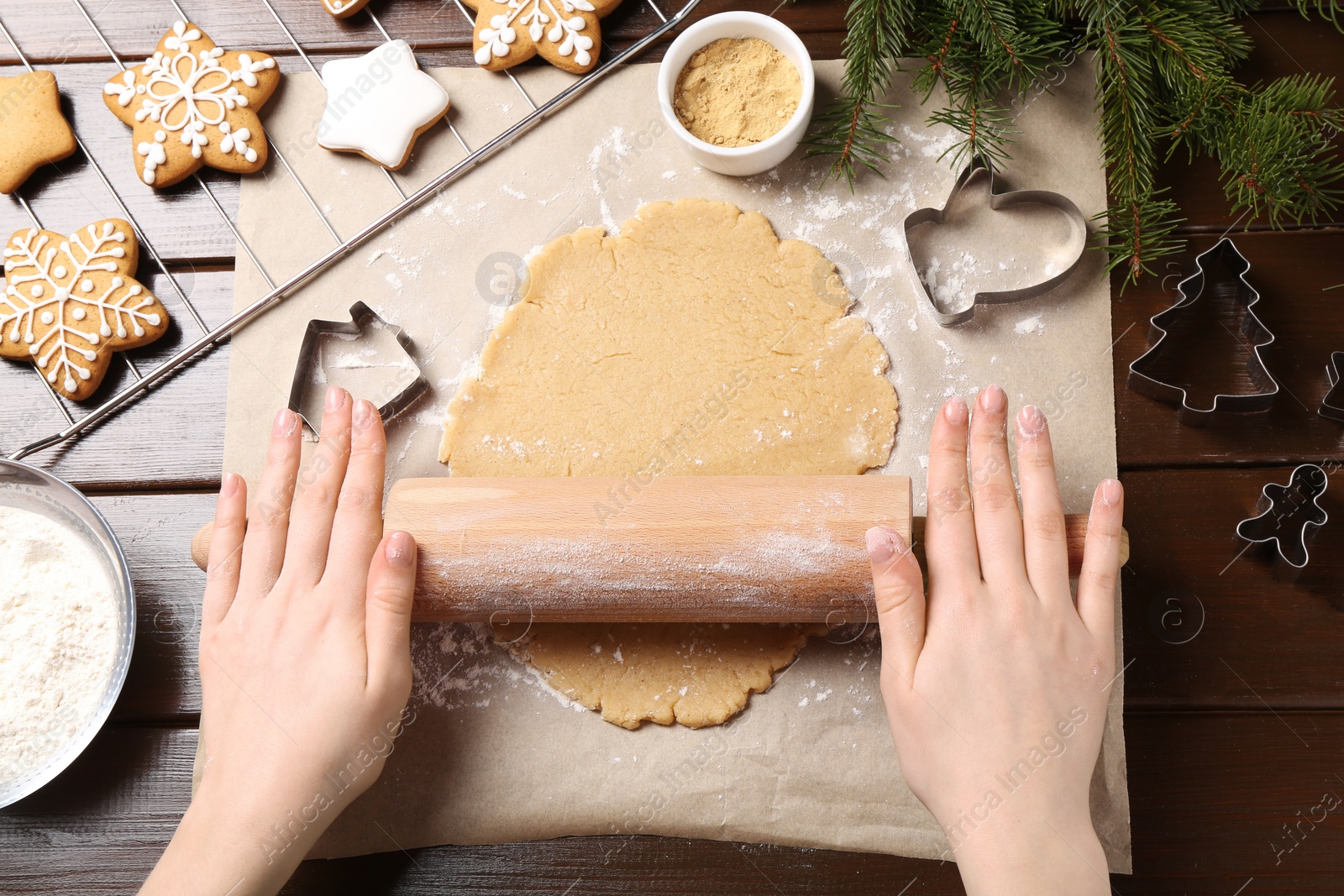 Photo of Making Christmas cookies. Woman rolling raw dough at wooden table, top view