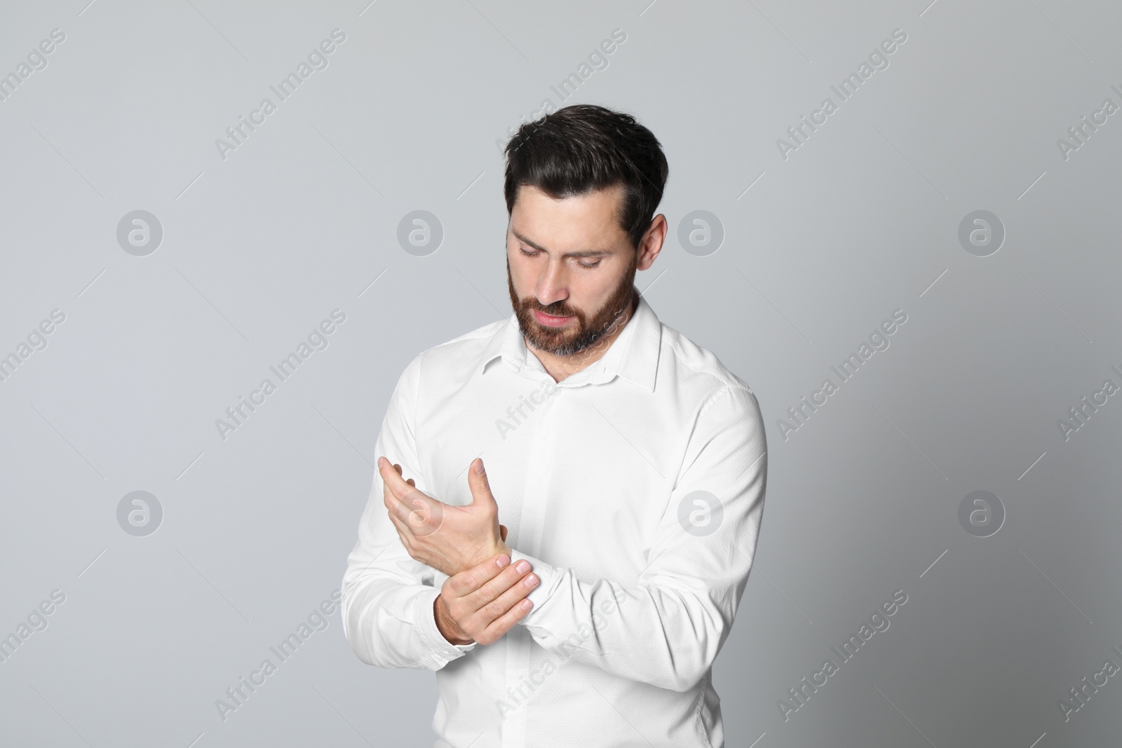 Photo of Man suffering from pain in his hand on light background. Arthritis symptoms