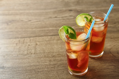 Glasses of refreshing iced tea on wooden table. Space for text