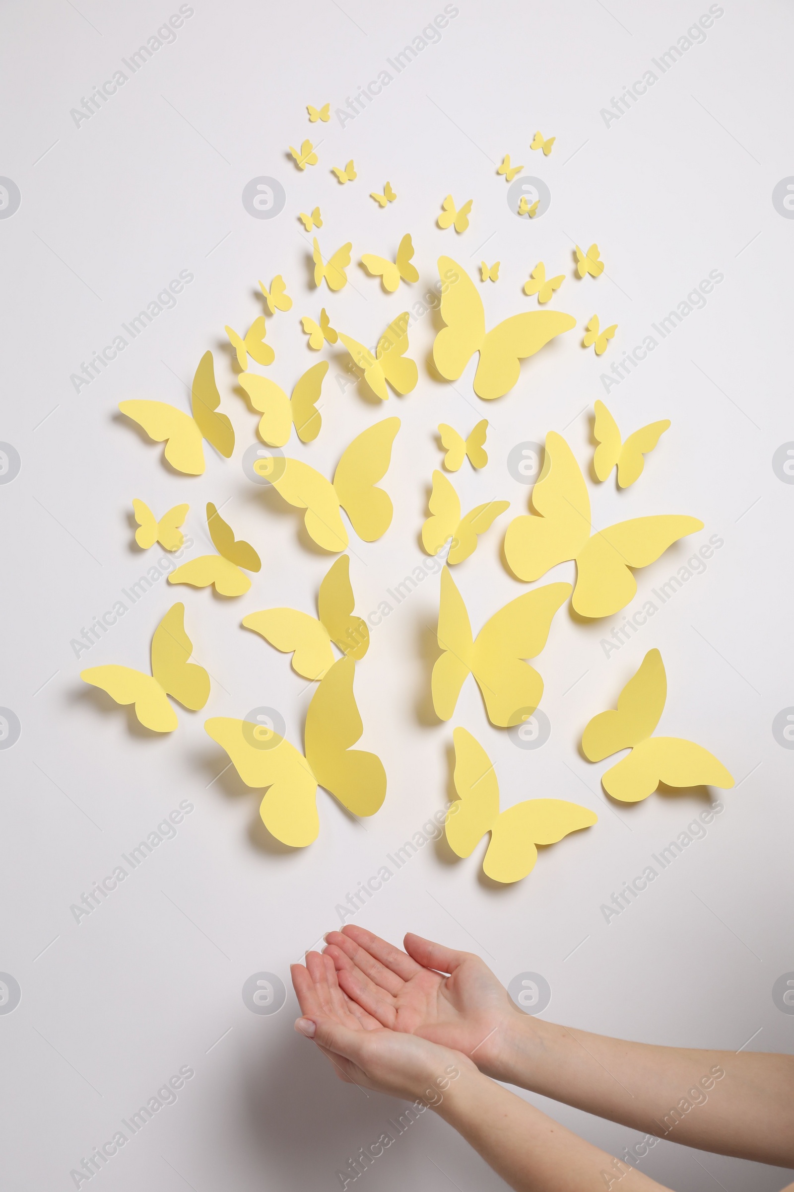 Photo of Woman with yellow paper butterflies on white background, top view