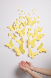 Woman with yellow paper butterflies on white background, top view