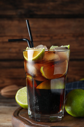 Photo of Glass of fresh Cuba Libre cocktail on wooden table, closeup