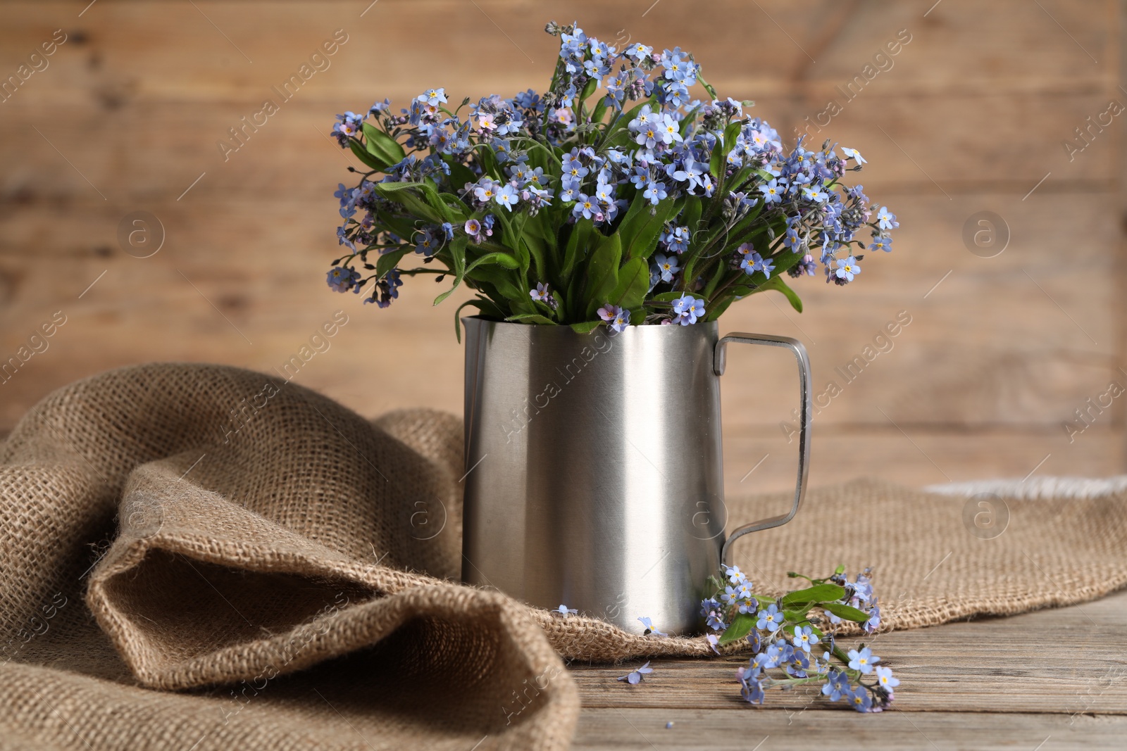 Photo of Beautiful forget-me-not flowers on wooden table, closeup