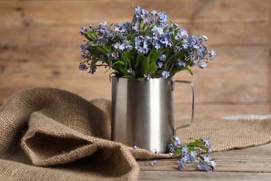 Photo of Beautiful forget-me-not flowers on wooden table, closeup