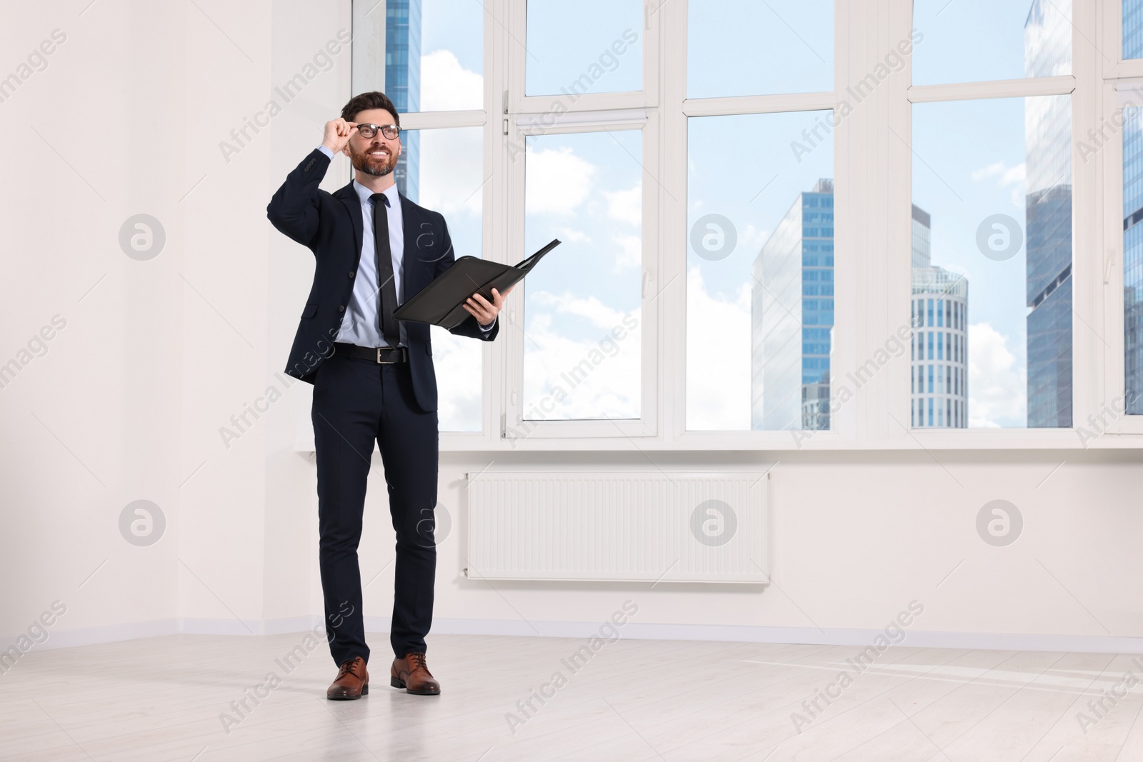 Photo of Handsome real estate agent with documents in empty room, space for text