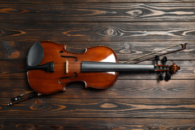 Photo of Classic violin and bow on wooden background, top view