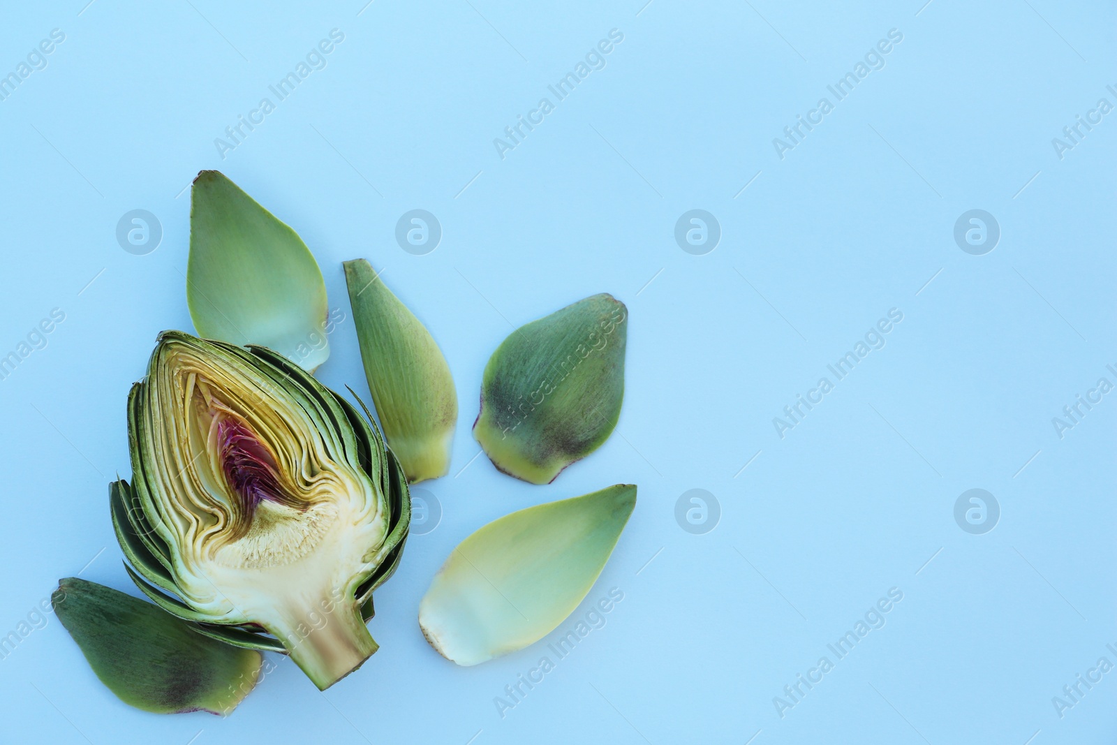 Photo of Half of fresh raw artichoke and leaves on white background, flat lay. Space for text