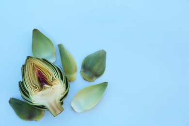 Photo of Half of fresh raw artichoke and leaves on white background, flat lay. Space for text