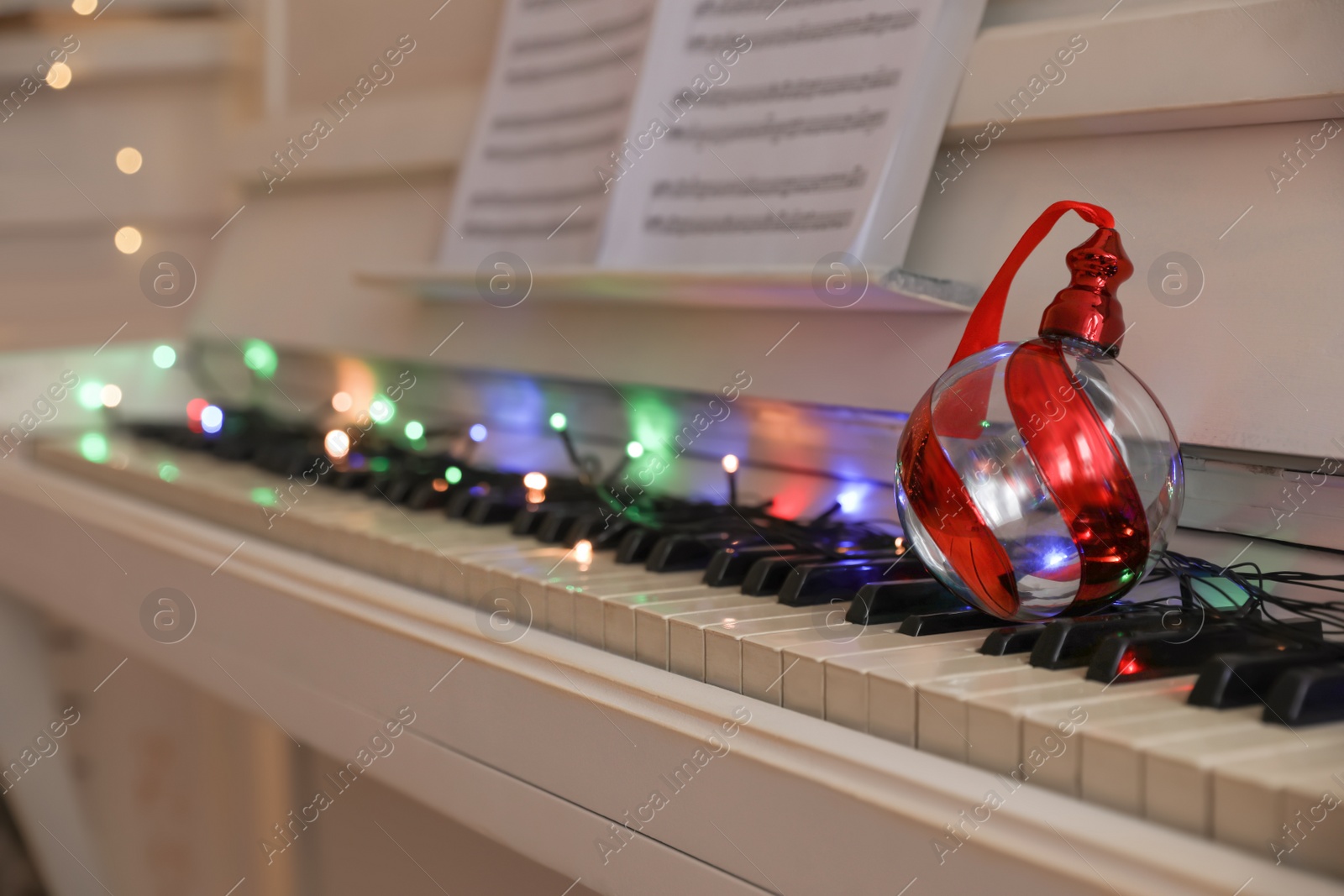 Photo of Beautiful bauble on piano keys indoors, space for text. Christmas music