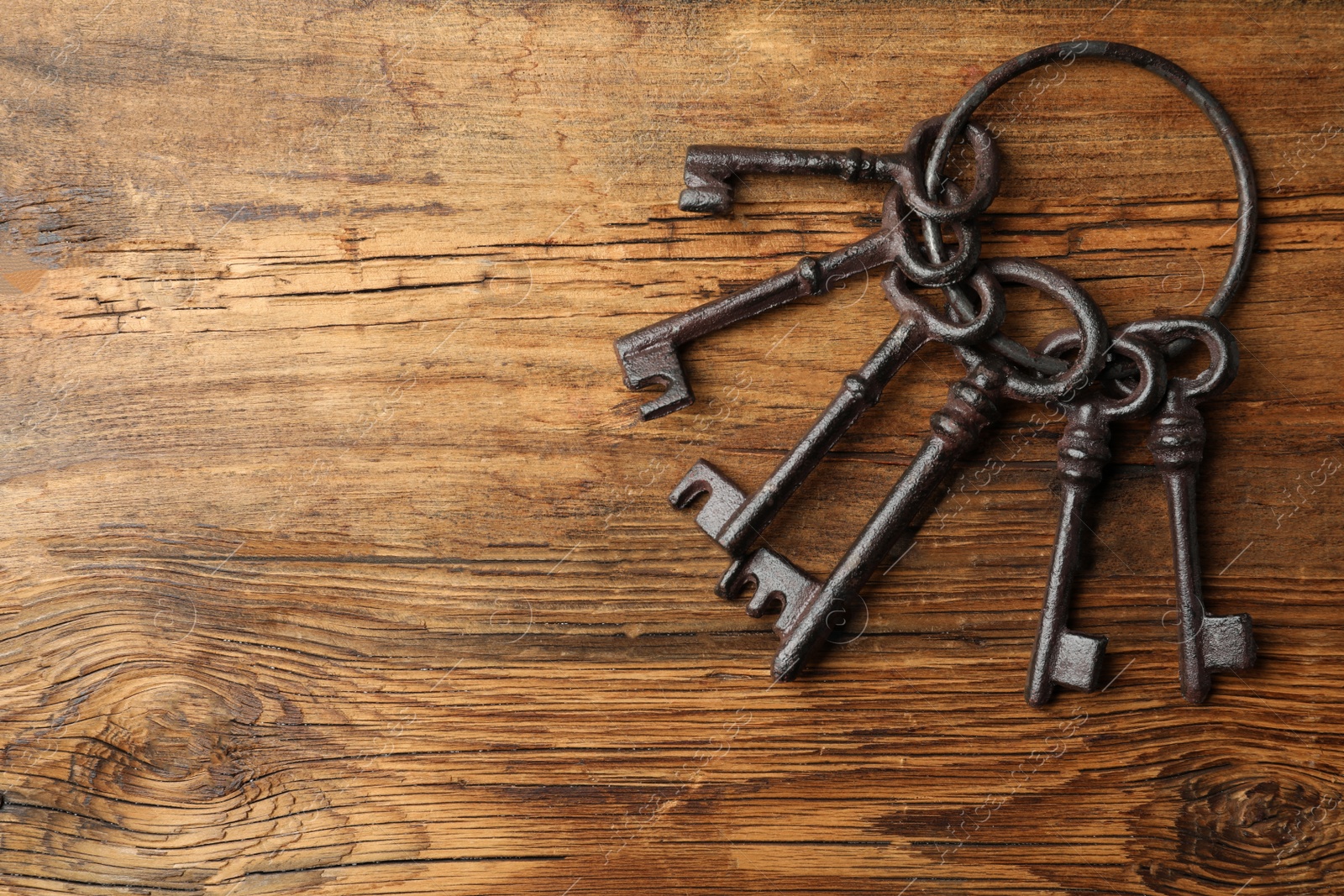 Photo of Bunch of steel keys on wooden background, top view with space for text. Safety concept