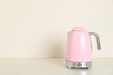 Photo of Modern electric kettle on counter in kitchen. Space for text