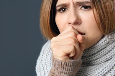 Photo of Woman suffering from cough on dark background, closeup. Space for text