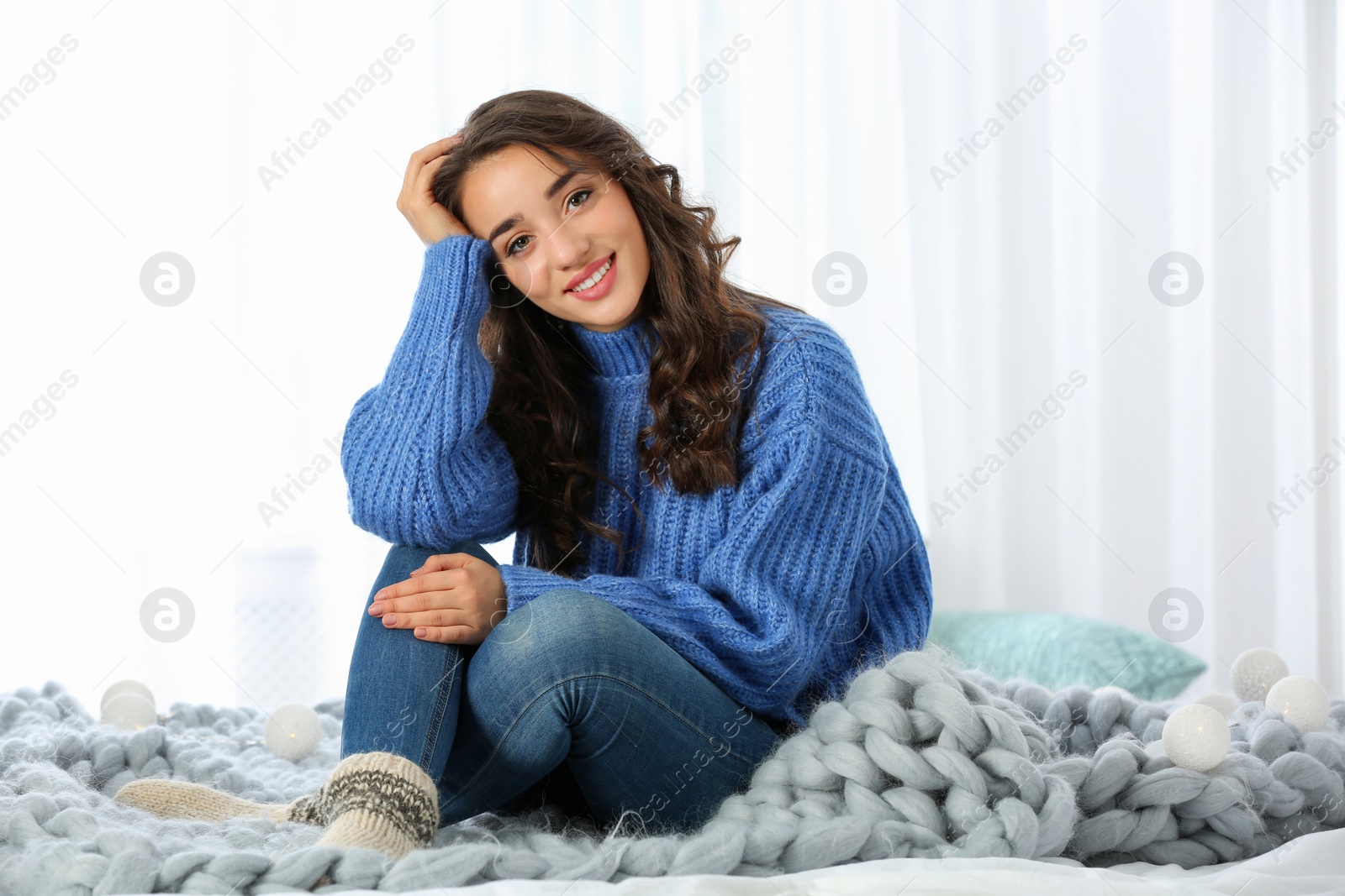 Photo of Young beautiful woman in warm sweater at home