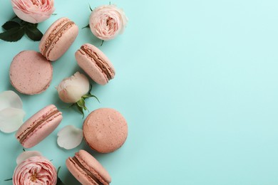 Photo of Flat lay composition with pink macarons and roses on light blue background. Space for text