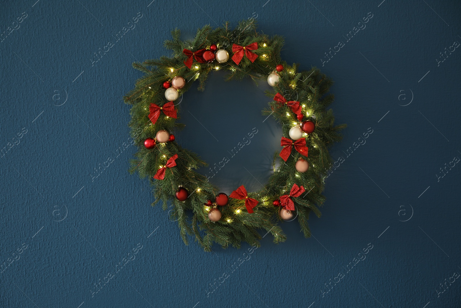 Photo of Beautiful Christmas wreath with festive decor on blue wall