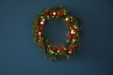 Photo of Beautiful Christmas wreath with festive decor on blue wall