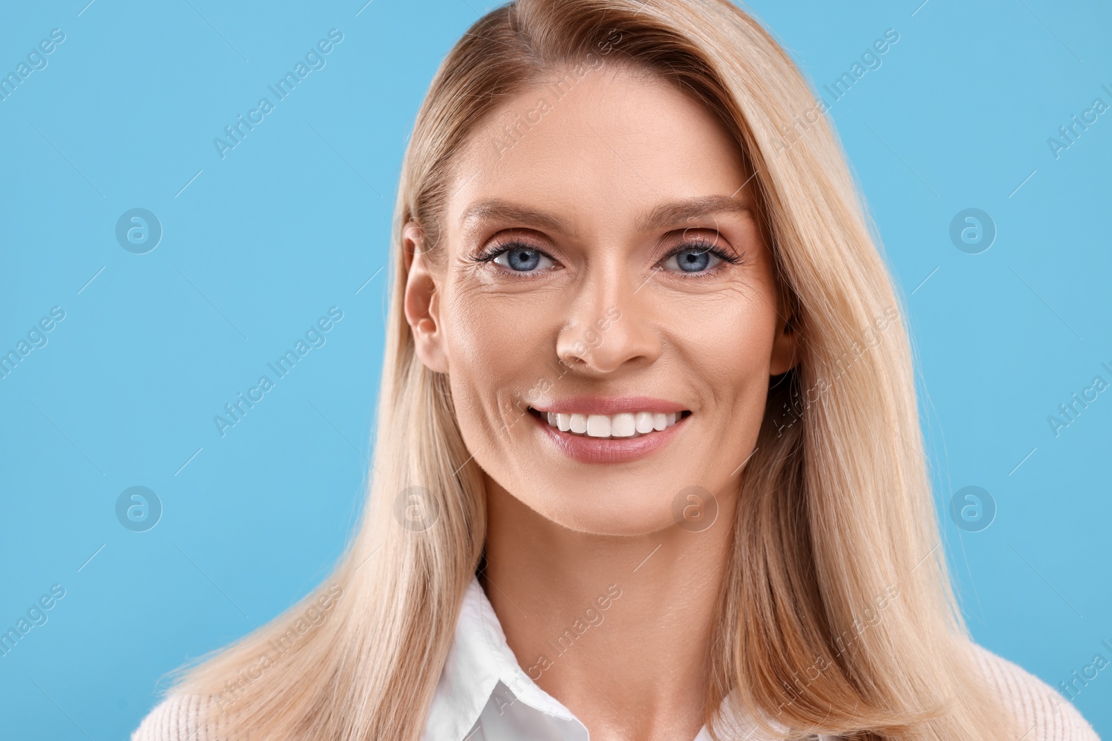 Photo of Portrait of smiling middle aged woman on light blue background