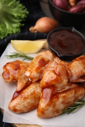Photo of Raw marinated chicken wings and rosemary on table, closeup