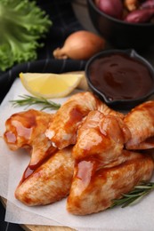 Raw marinated chicken wings and rosemary on table, closeup