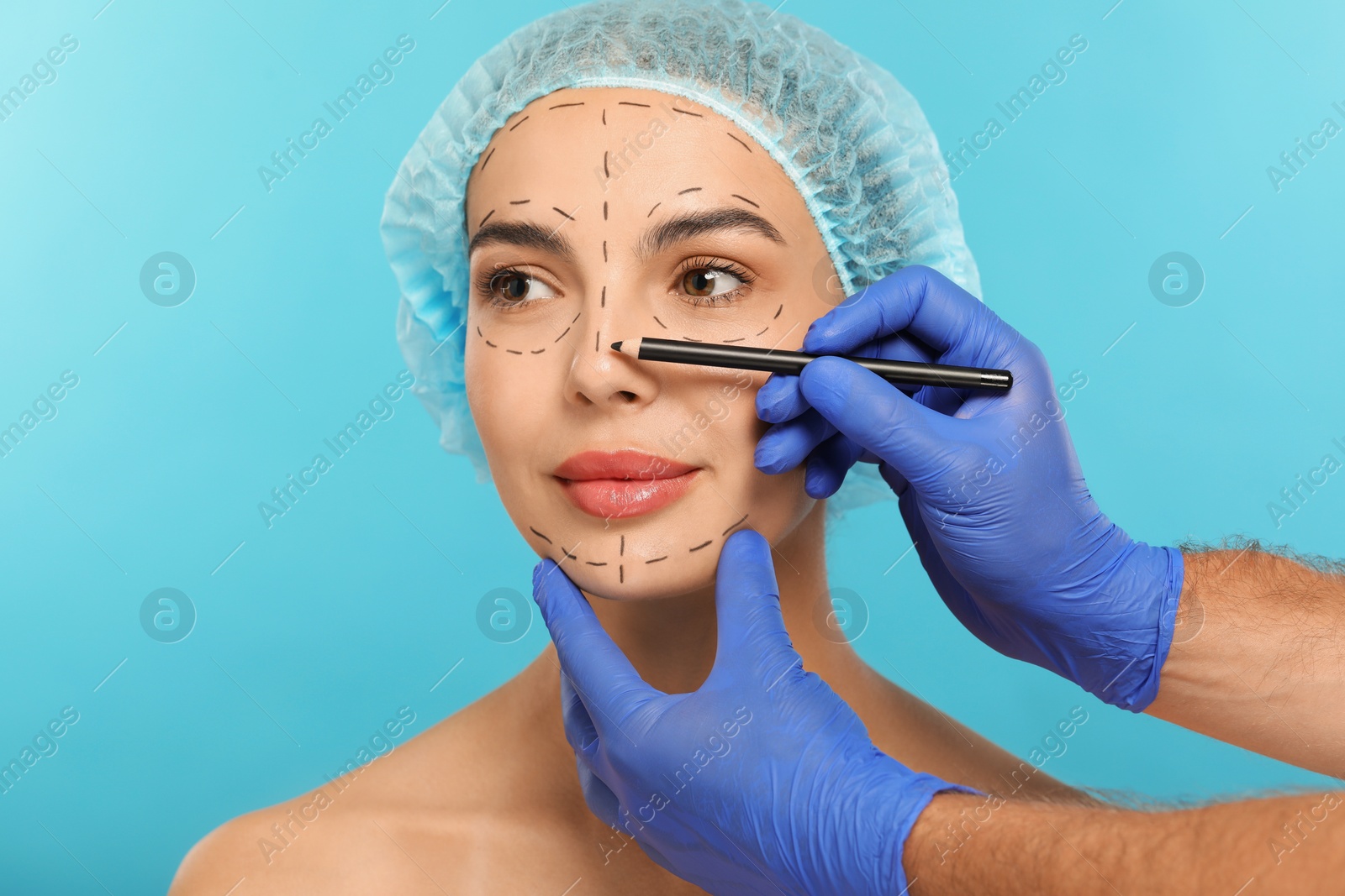 Photo of Doctor with pencil preparing patient for cosmetic surgery operation on light blue background, closeup