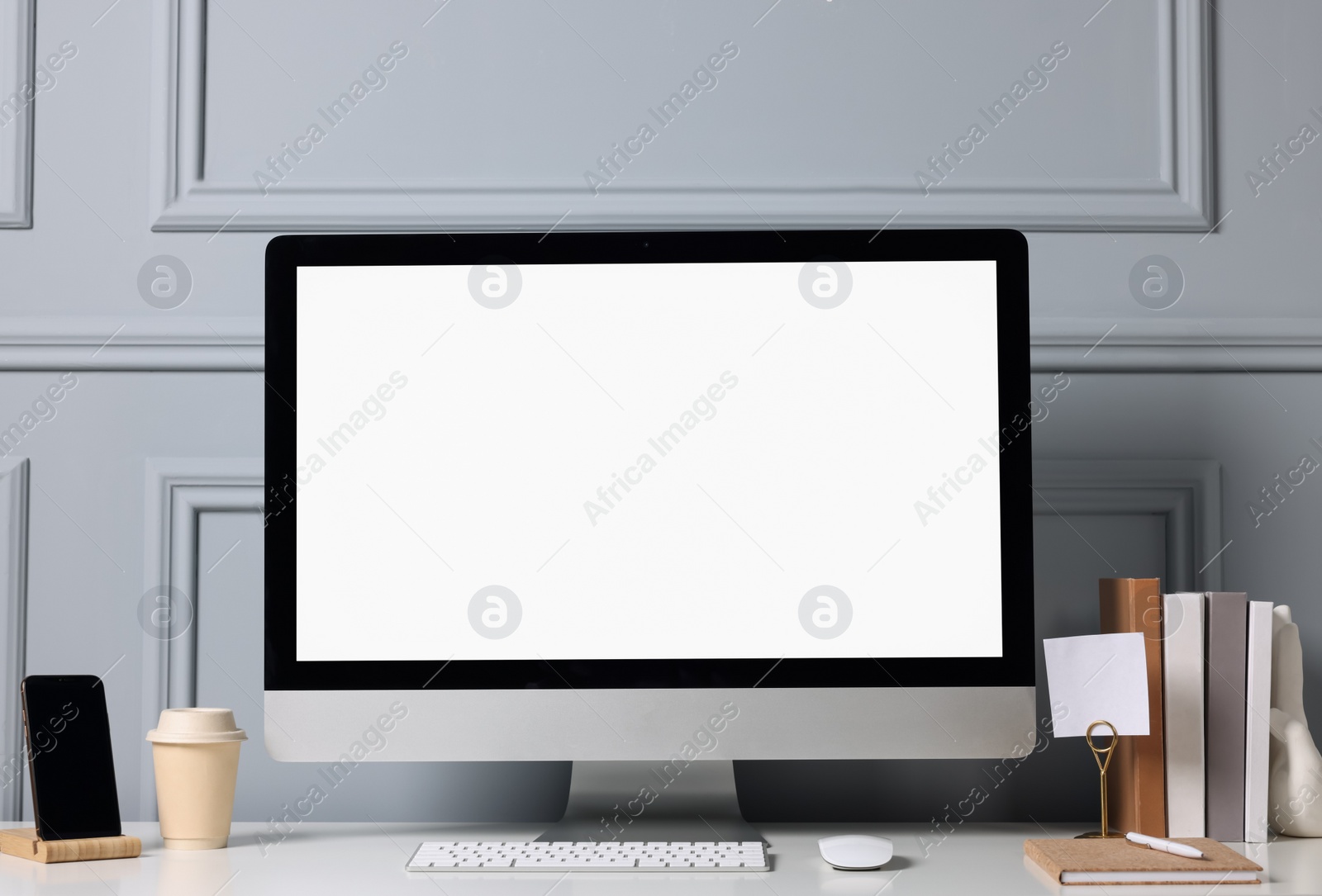 Photo of Cozy workspace with computer and stationery on white desk indoors