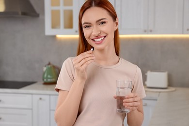 Photo of Beautiful young woman with vitamin pill and glass of water