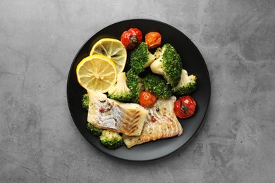 Tasty cod cooked with vegetables on grey table, top view
