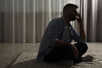 Photo of Sad man sitting on floor near window. Space for text