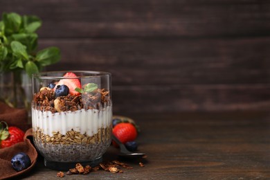 Photo of Tasty granola with berries, nuts, yogurt and chia seeds on wooden table, space for text