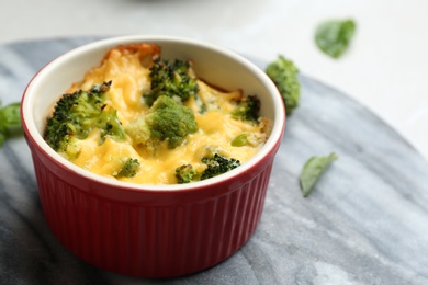 Photo of Tasty broccoli casserole in ramekin on table