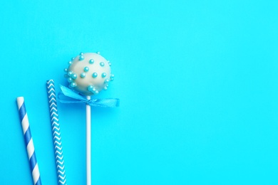 Photo of Tasty cake pop and straws on light blue background, flat lay. Space for text